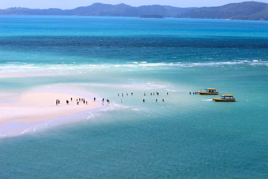 barcos anclados y turistas en Whitehaven Beach.