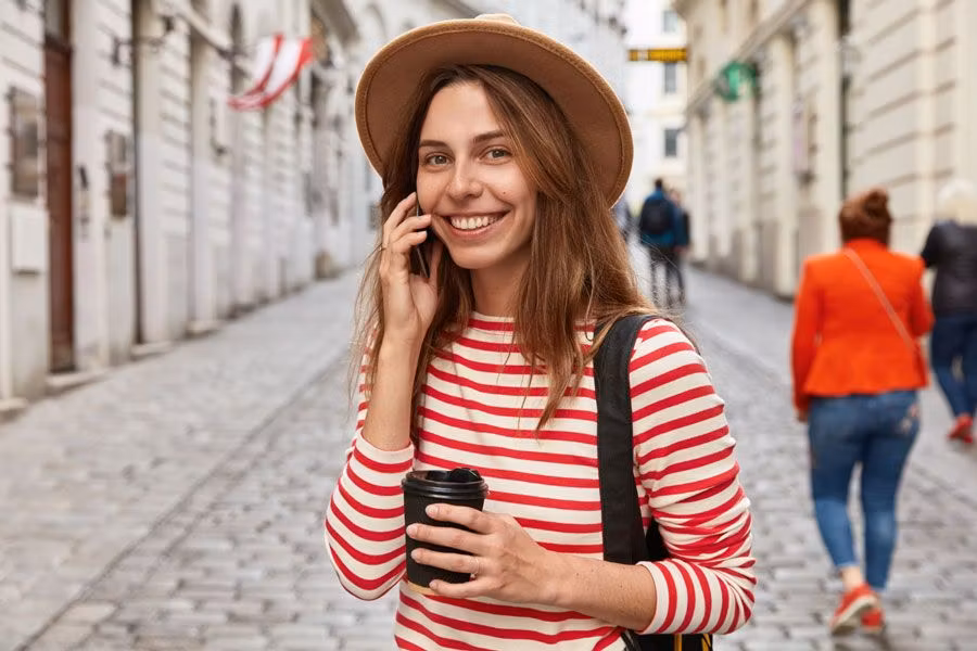 mujer de viaje sonriendo con un móvil