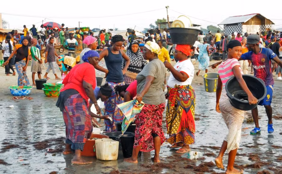 Mujeres esperan a los pescadores en la playa de Gambia