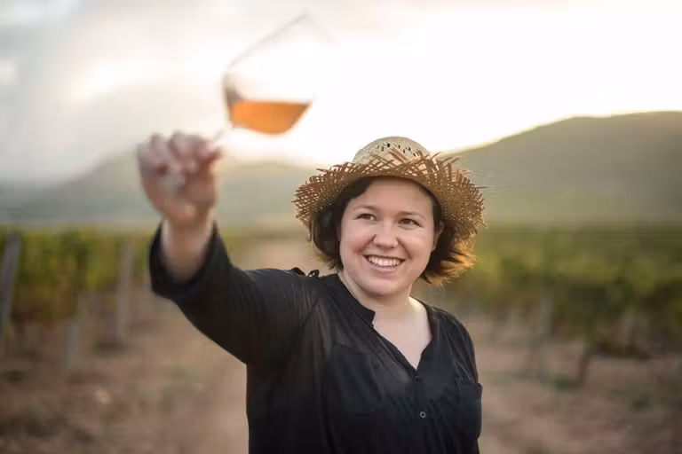 mujer con una copa de vino en un viñedo