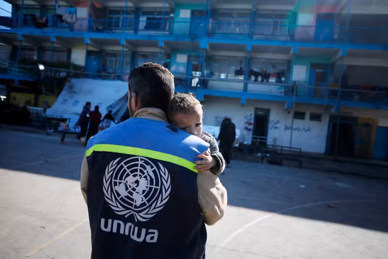 Un trabajador humanitario de UNRWA carga a un niño herido en el patio de una escuela convertida en refugio en el centro de Gaza, uno de los hasta 150 refugios de emergencia gestionados por UNRWA, enero de 2024.