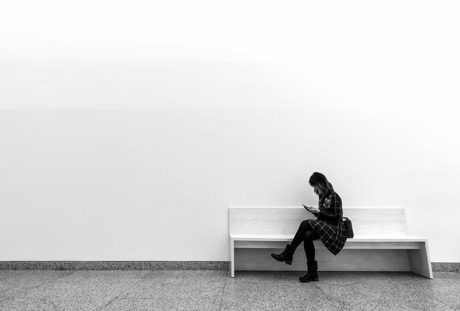 mujer consultado el móvil en un banco