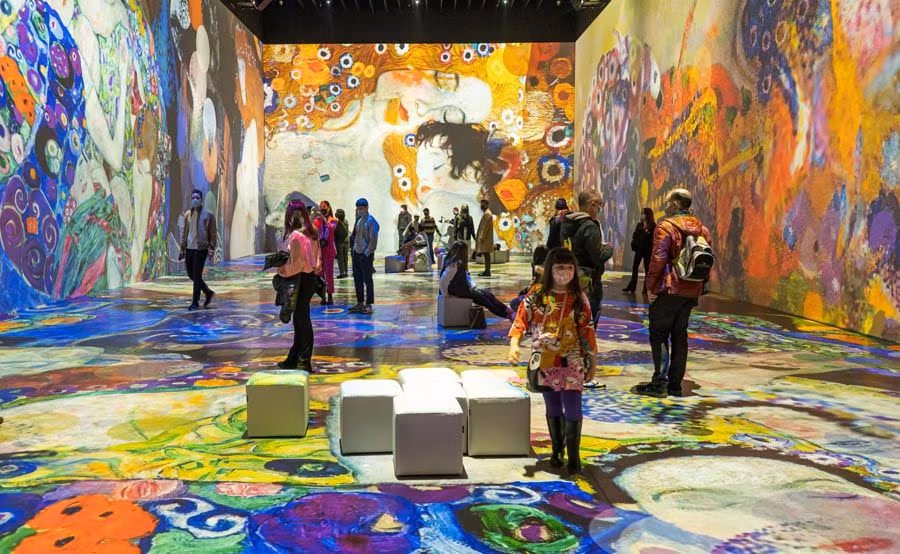 Personas de pie disfrutando de la exposicion de Klimt