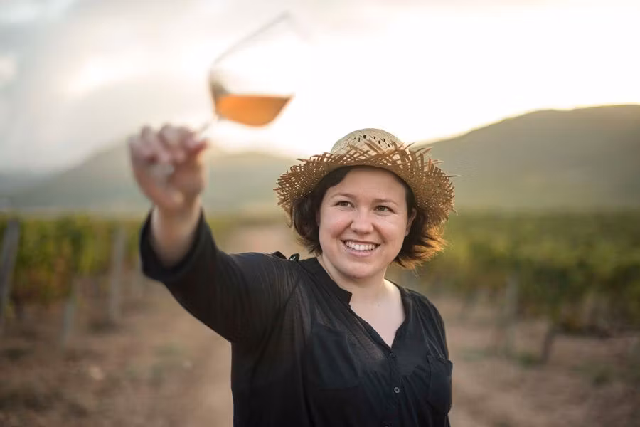 mujer con una copa de vino en un viñedo