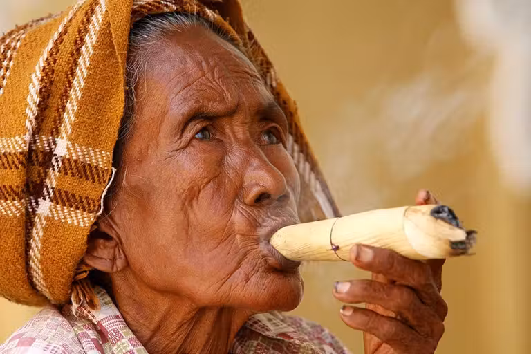 Una anciana birmana fuma un cigarro al acabar el día.