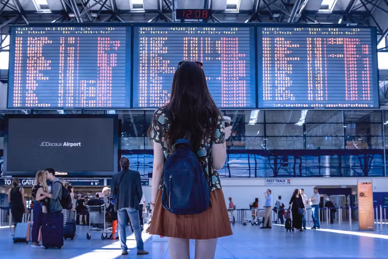 mujer mirando panel de aeropuerto
