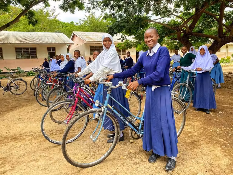 un grupo de niñas de Tanzania posa con una sonrisa con sus bicicletas