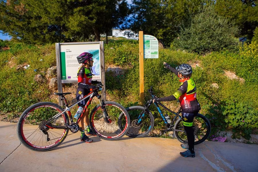dos ciclistas observan un cartel de un sendero en rute