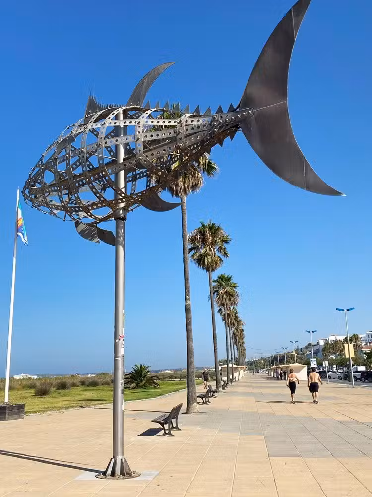 Paseo marítimo de Conil con un escultura de un atún en primer plano.