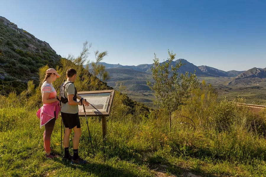 una pareja lee un cartel mientras hace una ruta senderista en carcabuey, una parada de la Ruta en autocaravana por la Subbética Cordobesa