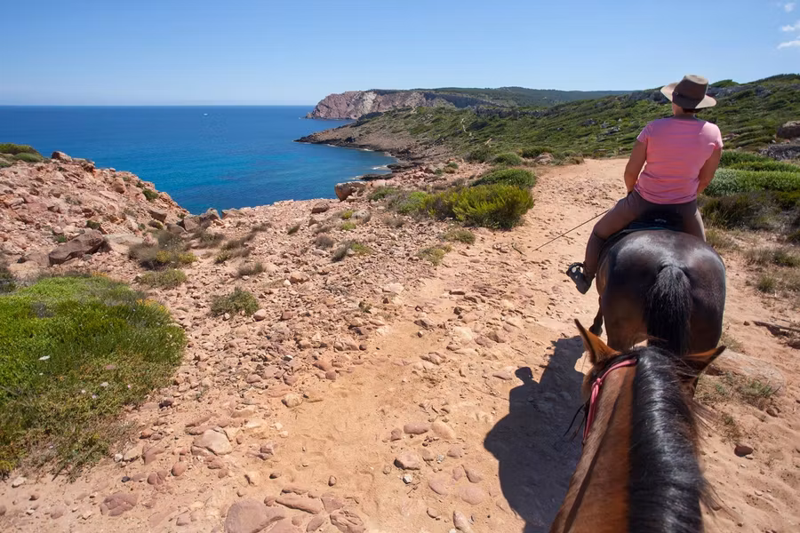 mujer a caballo en el Camí de Cavalls en Menorca