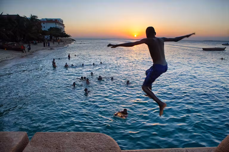 Un joven salta al atardecer en una playa de Stone Town.