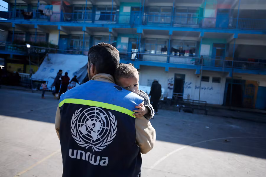 Un trabajador humanitario de UNRWA carga a un niño herido en el patio de una escuela convertida en refugio en el centro de Gaza, uno de los hasta 150 refugios de emergencia gestionados por UNRWA, enero de 2024.