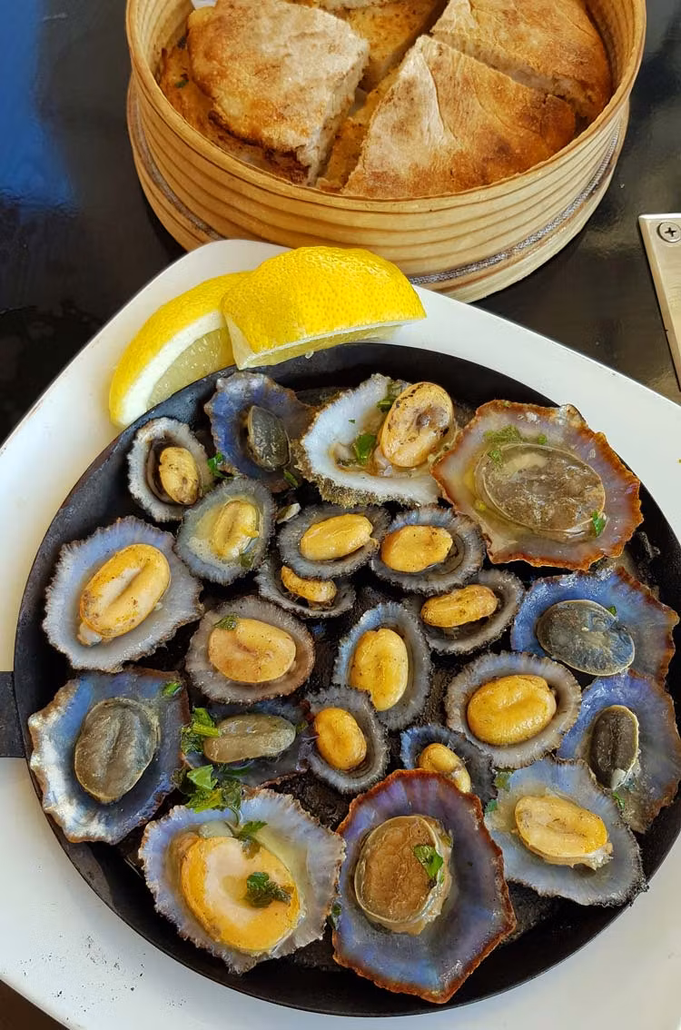 Lapas a la parrilla con bolo de caco al fondo.
