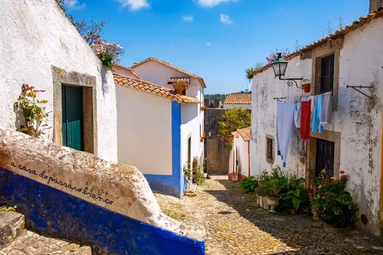 Un coqueto rincón de Óbidos con casas blancas y ropa tendida.