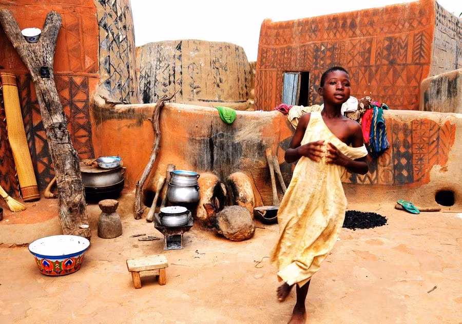 Una niña junto a su casa pintada de Tiebele